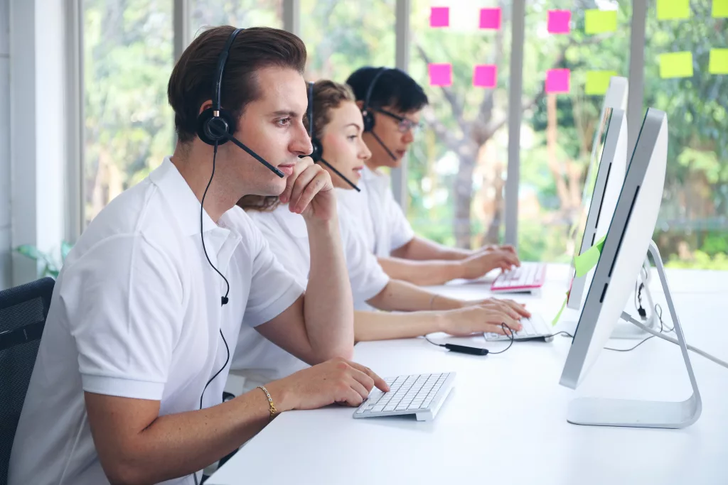 Business people working in a Call Centre working with headsets on in front of computers